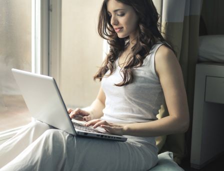 Designer working on a laptop by a sunny window